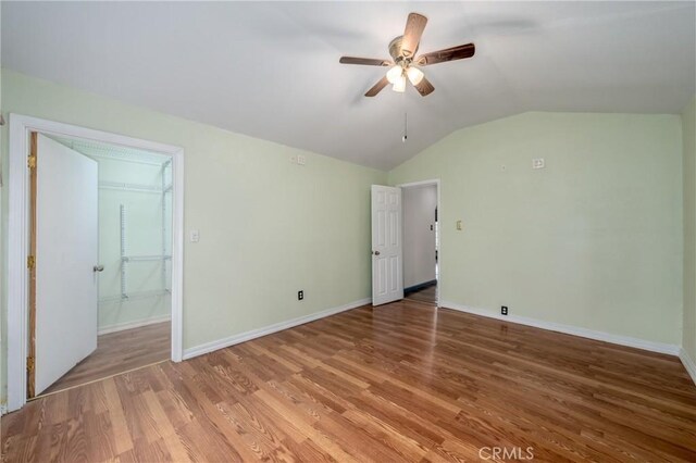 unfurnished bedroom with lofted ceiling, hardwood / wood-style floors, and ceiling fan