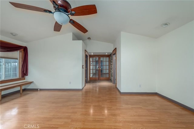 spare room with vaulted ceiling, light hardwood / wood-style floors, and french doors