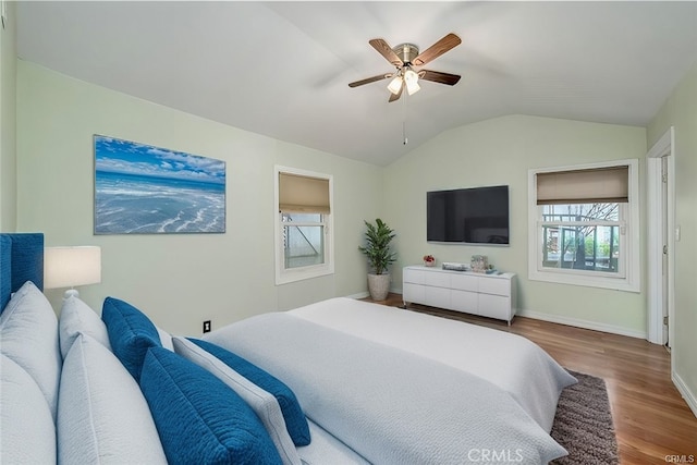 bedroom featuring hardwood / wood-style flooring, ceiling fan, multiple windows, and lofted ceiling