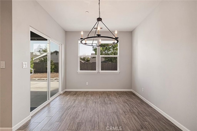 unfurnished dining area with wood-type flooring and a notable chandelier