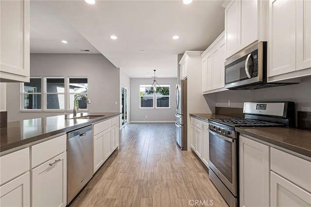 kitchen with stainless steel appliances, decorative light fixtures, sink, and white cabinets