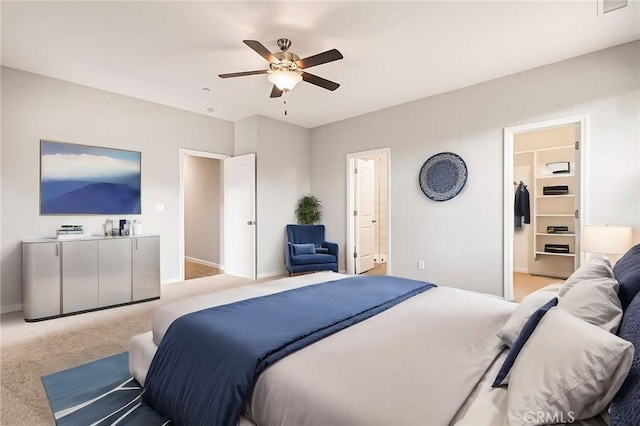 carpeted bedroom featuring a spacious closet, connected bathroom, and ceiling fan