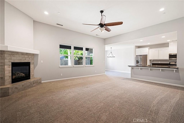 living room featuring ceiling fan, carpet flooring, sink, and a brick fireplace