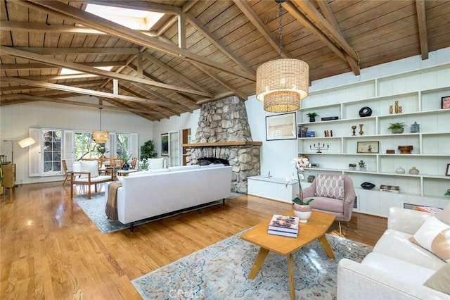 living room featuring lofted ceiling with skylight, a stone fireplace, wood ceiling, a chandelier, and light wood-type flooring