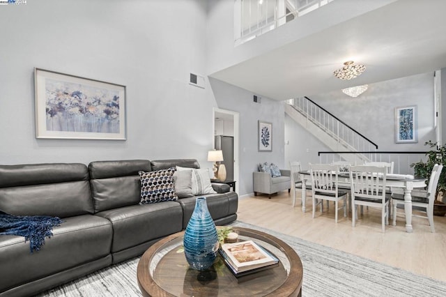 living room featuring a high ceiling, wood-type flooring, and a notable chandelier