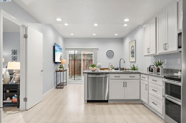 kitchen featuring white cabinetry, stainless steel appliances, sink, and light wood-type flooring