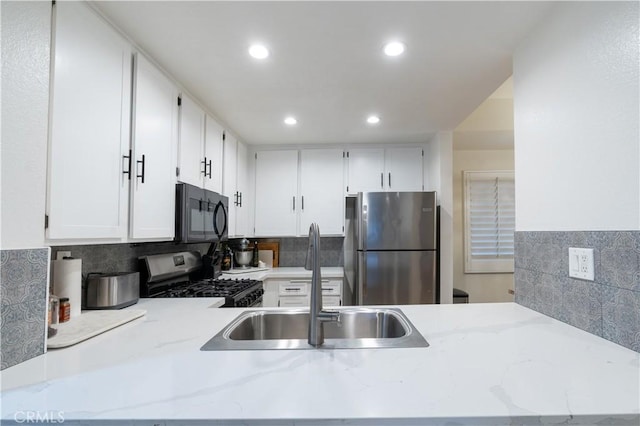 kitchen with white cabinetry, appliances with stainless steel finishes, sink, and tasteful backsplash