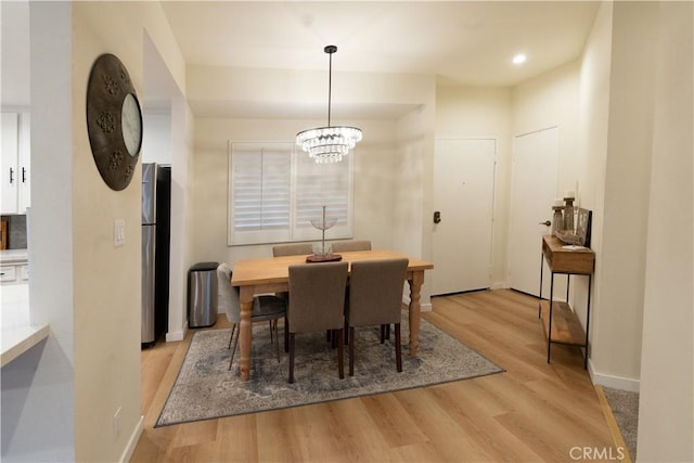 dining area with a notable chandelier and light hardwood / wood-style floors