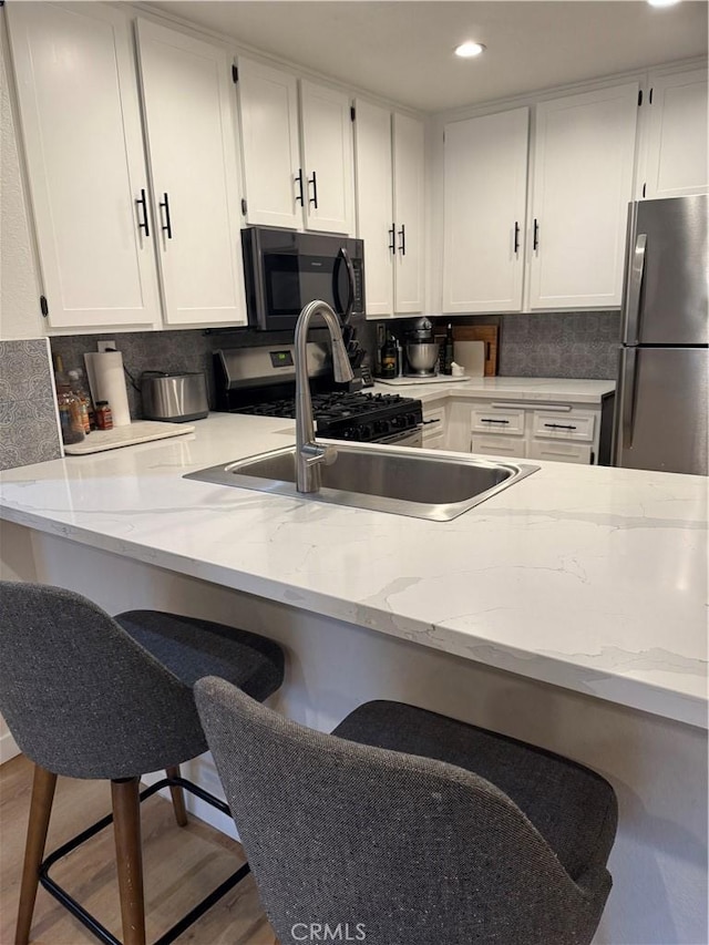 kitchen featuring a kitchen bar, stainless steel fridge, and white cabinets