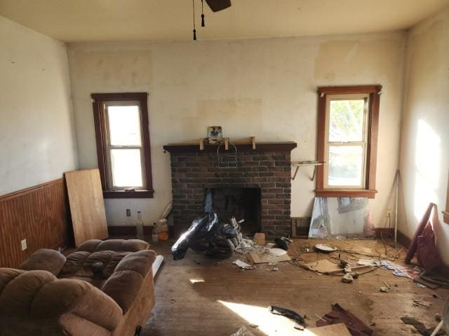 miscellaneous room with ceiling fan, a brick fireplace, and wood walls