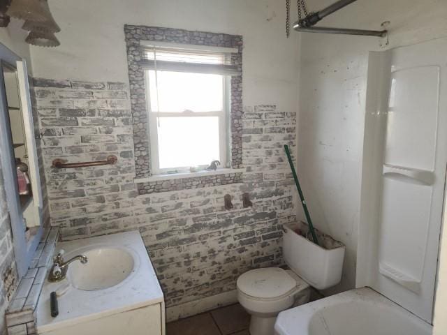 bathroom featuring tile patterned floors, vanity, toilet, and brick wall