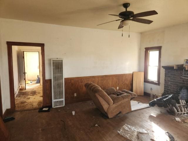 living room with dark wood-type flooring, a fireplace, ceiling fan, and wood walls