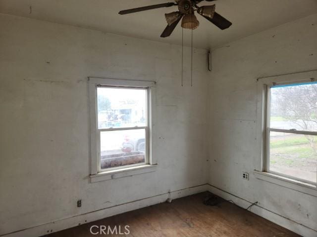 empty room with ceiling fan, dark hardwood / wood-style floors, and a wealth of natural light