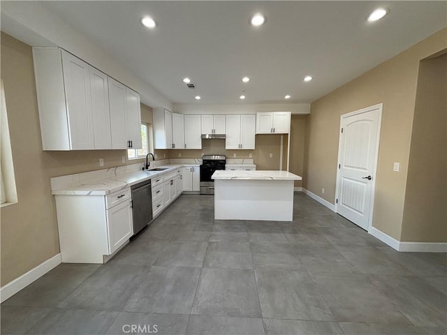 kitchen with sink, appliances with stainless steel finishes, light stone countertops, white cabinets, and a kitchen island