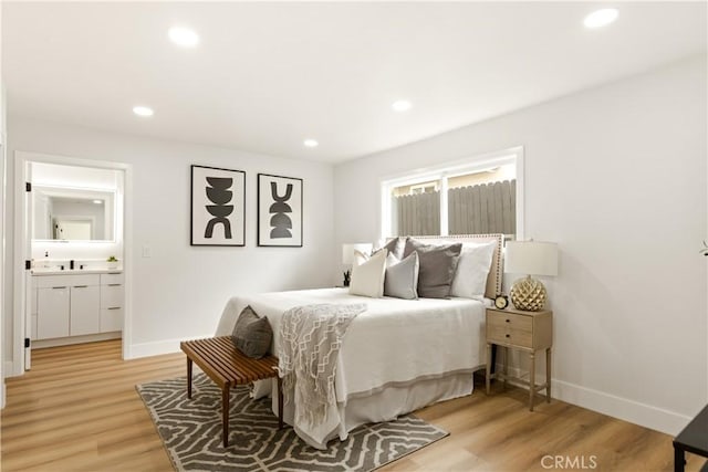 bedroom featuring sink, ensuite bath, and light hardwood / wood-style floors