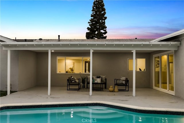 back house at dusk featuring a patio