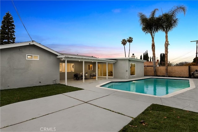 pool at dusk featuring a patio area