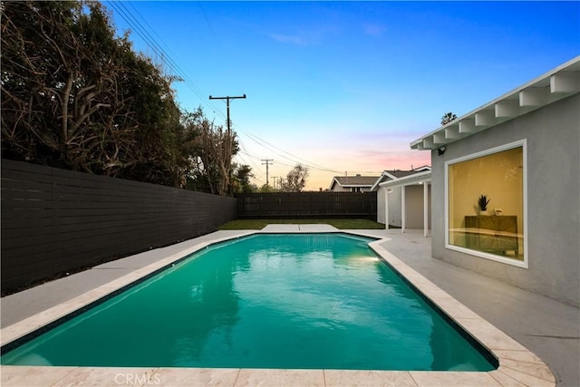 pool at dusk with a patio area