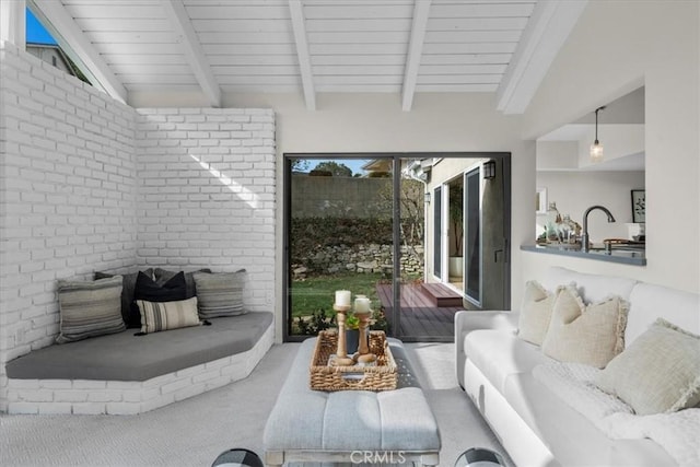 living room featuring carpet floors, sink, and lofted ceiling with beams