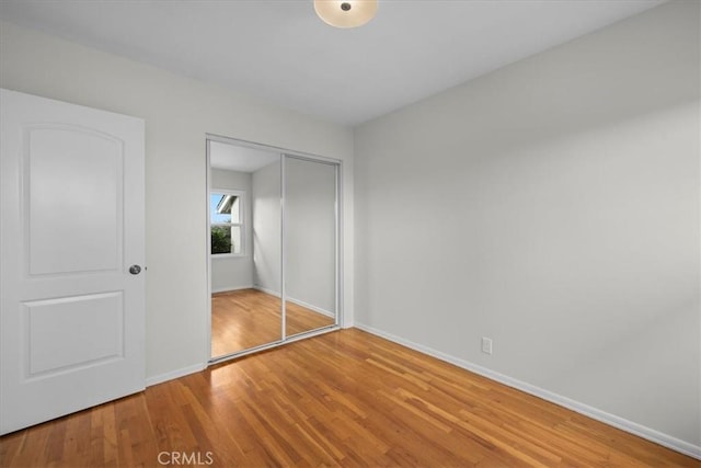 unfurnished bedroom with a closet, baseboards, and wood finished floors