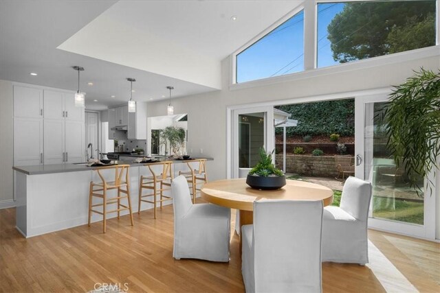 dining room featuring sink, light hardwood / wood-style floors, and a high ceiling