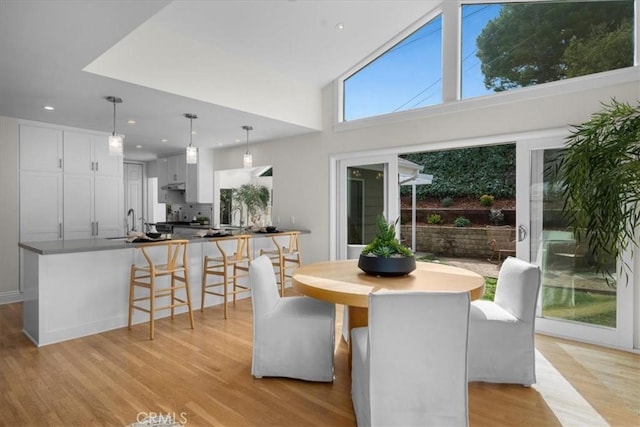 dining area featuring recessed lighting, light wood-type flooring, and a towering ceiling