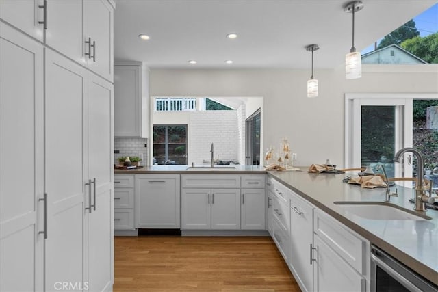 kitchen featuring white cabinetry, sink, decorative light fixtures, and plenty of natural light