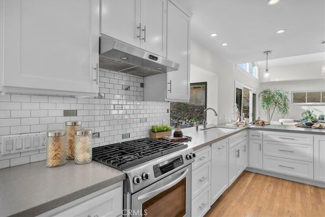 kitchen featuring light wood-style flooring, under cabinet range hood, a sink, white cabinetry, and stainless steel range with gas stovetop