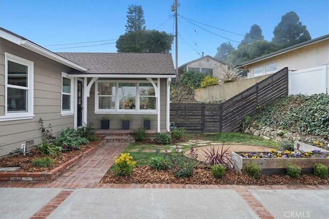 property entrance featuring a shingled roof and fence