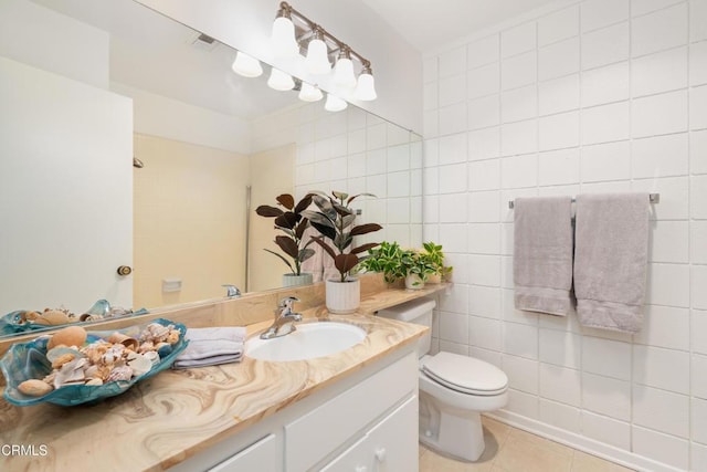 bathroom with tile walls, vanity, tile patterned flooring, and toilet