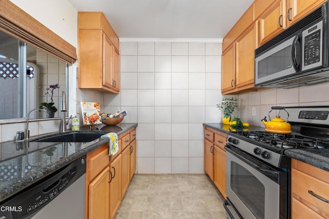 kitchen featuring stainless steel appliances, sink, decorative backsplash, and dark stone counters