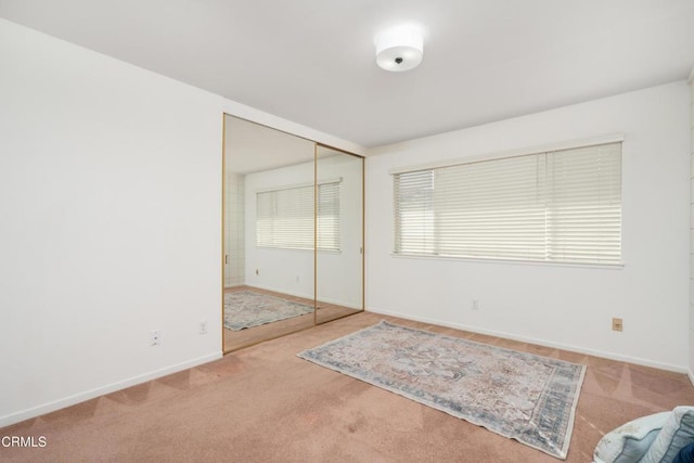 unfurnished bedroom featuring light colored carpet and a closet