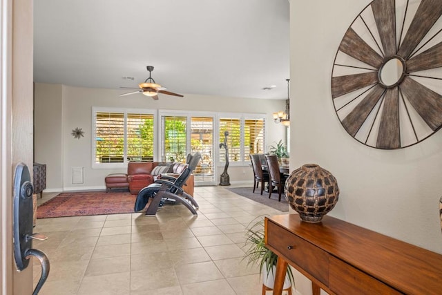 living room featuring light tile patterned floors, ceiling fan with notable chandelier, and a healthy amount of sunlight