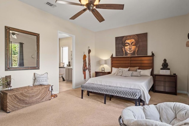 bedroom with ceiling fan, light colored carpet, and connected bathroom