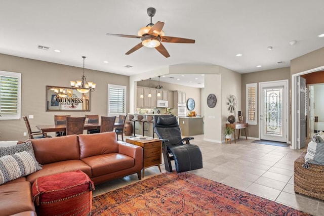 tiled living room with ceiling fan with notable chandelier