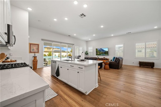 kitchen featuring white cabinetry, a kitchen island, a wealth of natural light, stainless steel appliances, and light hardwood / wood-style floors