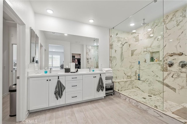 bathroom featuring hardwood / wood-style floors, vanity, and a tile shower