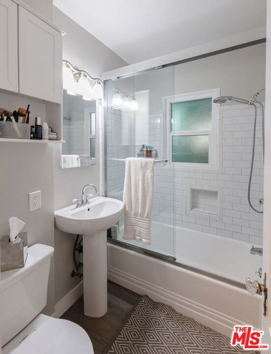 bathroom featuring enclosed tub / shower combo and toilet