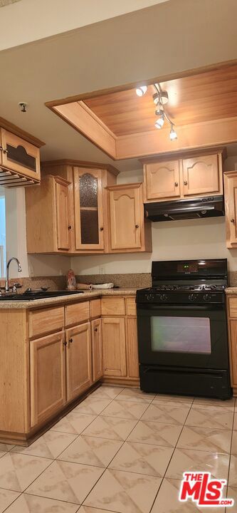 kitchen featuring black gas range, light brown cabinetry, wood ceiling, and sink