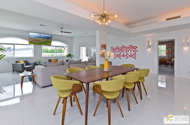 dining area featuring a tray ceiling, a chandelier, and light tile patterned floors