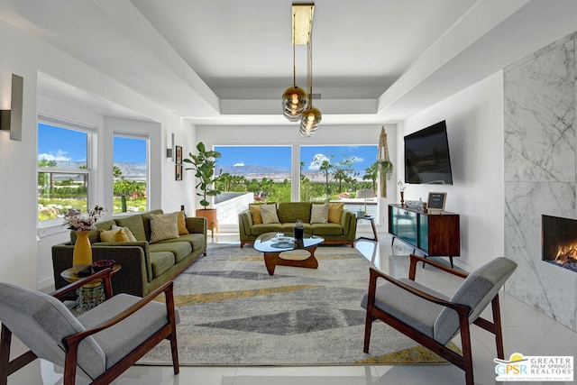 living room featuring a wealth of natural light, a fireplace, and a tray ceiling