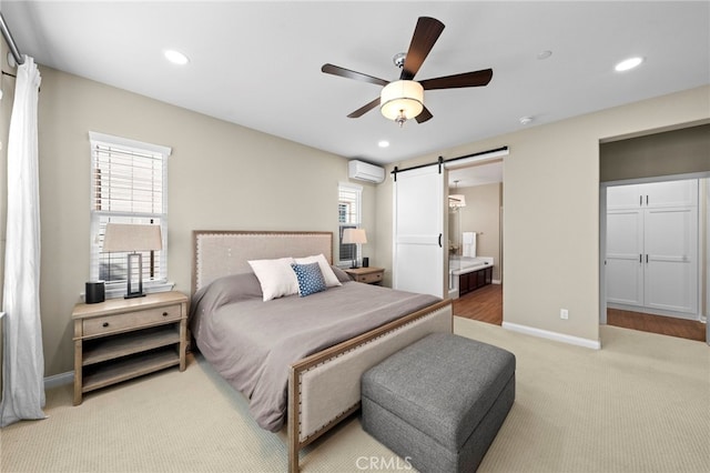 bedroom featuring ensuite bath, an AC wall unit, carpet flooring, ceiling fan, and a barn door