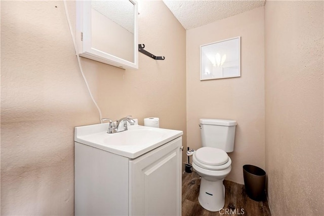 bathroom featuring vanity, toilet, wood-type flooring, and a textured ceiling