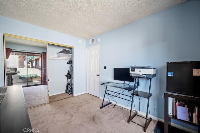 carpeted office featuring a textured ceiling