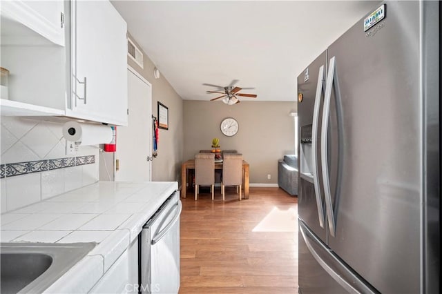 kitchen with tile countertops, stainless steel appliances, and white cabinets