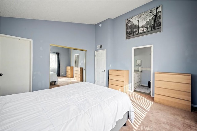 carpeted bedroom featuring ensuite bathroom, high vaulted ceiling, and a closet