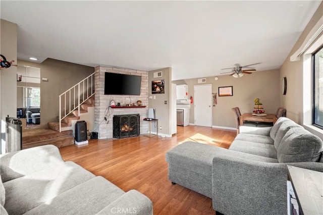 living room with ceiling fan, hardwood / wood-style floors, and a brick fireplace