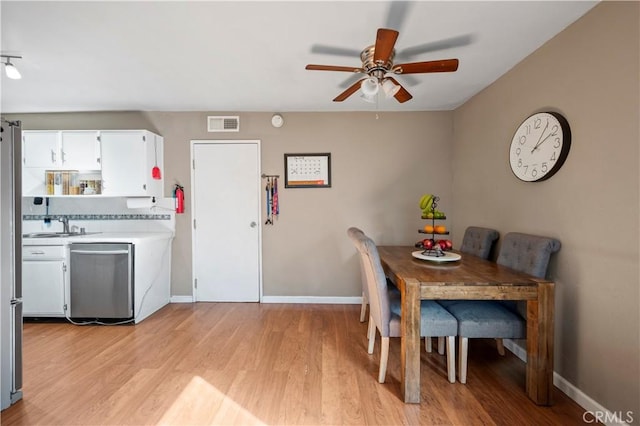 dining area with ceiling fan, sink, and light wood-type flooring