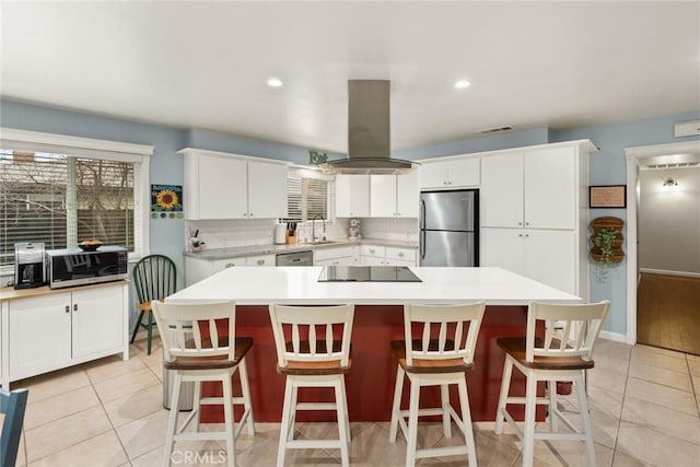 kitchen with sink, a kitchen island, island exhaust hood, and appliances with stainless steel finishes