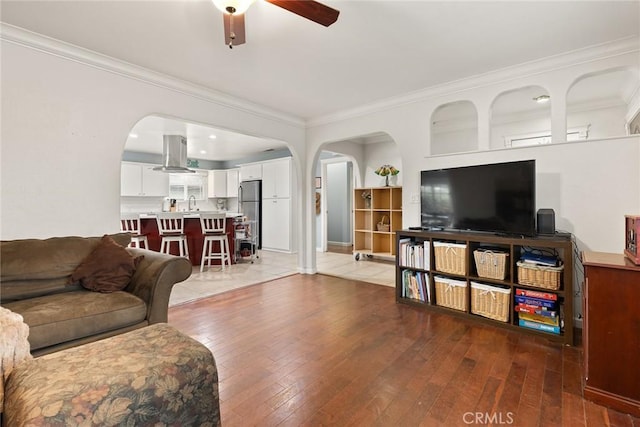 living room featuring ornamental molding, dark wood-type flooring, sink, and ceiling fan